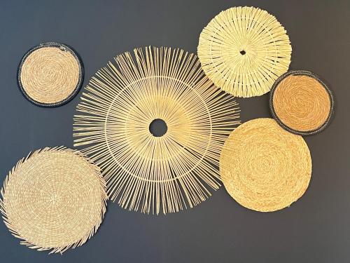 four straw umbrellas hanging on a wall at La maison de Louise in Sizun