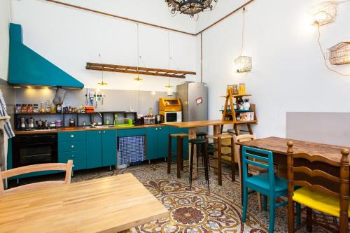 ジェノヴァにあるOStellin Genova Hostelのキッチン(青いキャビネット、木製テーブル付)