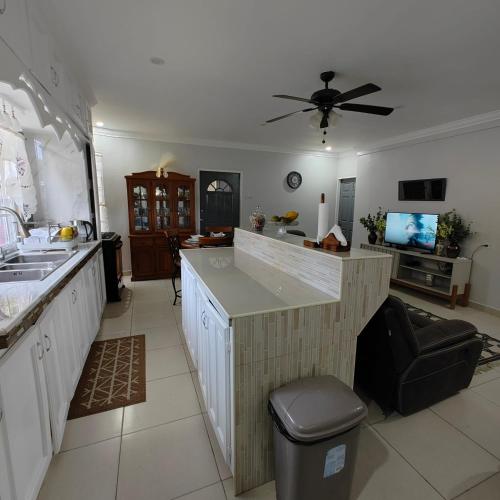 a kitchen with a counter with a sink and a tv at Furnished 2-Bedroom Flat for Rent in Diego Martin