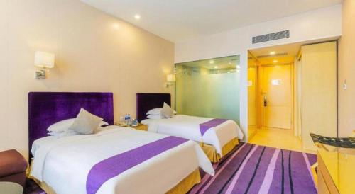 a hotel room with two beds with purple sheets at The Bauhinia in Shenzhen