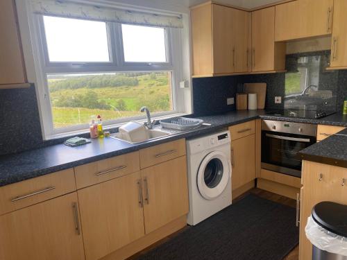 a kitchen with a sink and a washing machine at Alltachbeg in Tomintoul