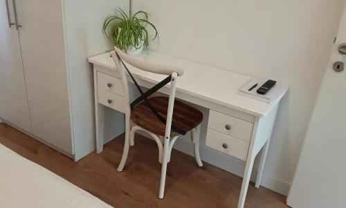 a white desk with a chair and a plant at Apartman Vlatka in Kninsko Polje