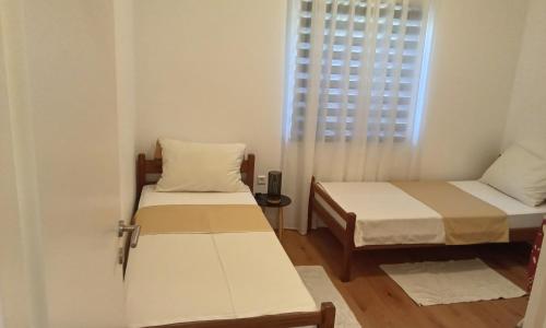 a small room with two beds and a window at Apartman Vlatka in Kninsko Polje