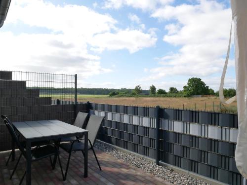 a patio with a table and chairs and a view of a field at Kelm's Küstennest 1 - 5 Fahrradminuten vom Strand entfernt in Kolpinsee