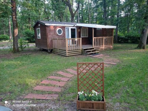 une petite cabane dans une cour avec un porche et des fleurs dans l'établissement Ile de France, mobil-home cosy au coeur d' une forêt avec piscine, à Saint-Chéron