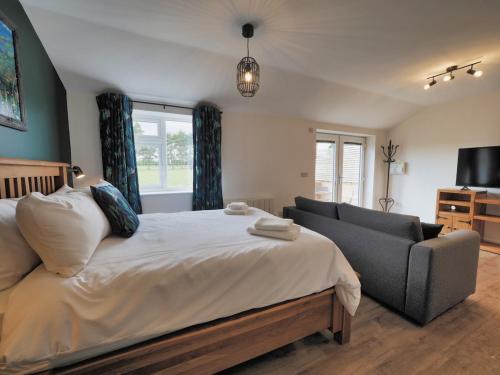 a bedroom with a bed and a couch and a television at Loxley's Lodge at Edwinstowe in Edwinstowe