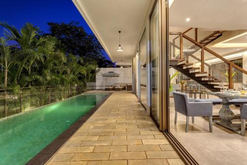 an infinity pool in a villa with a dining area and a house at Dia Hotels and Homes Nerul Goa - Villas and Apartments in Nerul