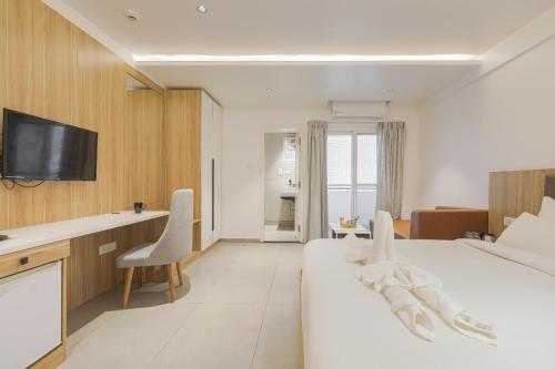 WhitefieldにあるAkoya Business Hotel Whitefieldのベッドとデスクが備わる白いホテルルームです。