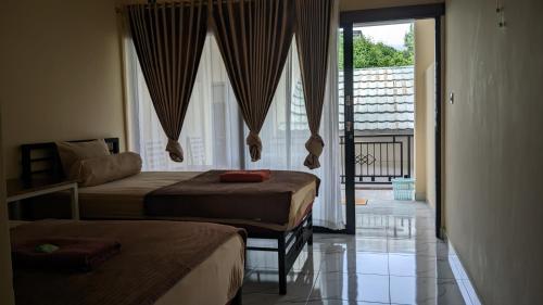 a hotel room with two beds and a balcony at Rinjani Homestay Senaru in Senaru