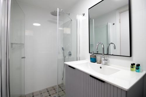 a white bathroom with a sink and a shower at Villa Ono at Bar Ilan University and Sheba Hospital in Qiryat Ono