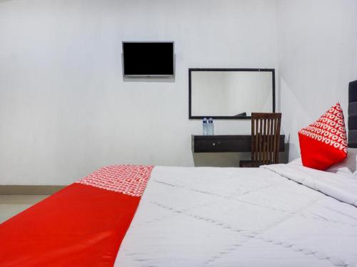 a bedroom with a red and white bed and a desk at Capital O 91534 Wisma Metro Permai in Makassar