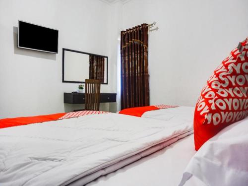 a bedroom with two beds and a flat screen tv at Capital O 91534 Wisma Metro Permai in Makassar