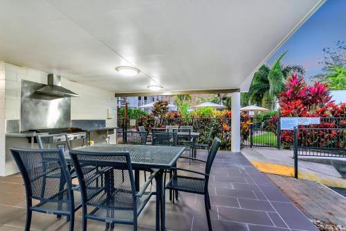a patio with a table and chairs and a kitchen at Barrier Townhouse in Port Douglas