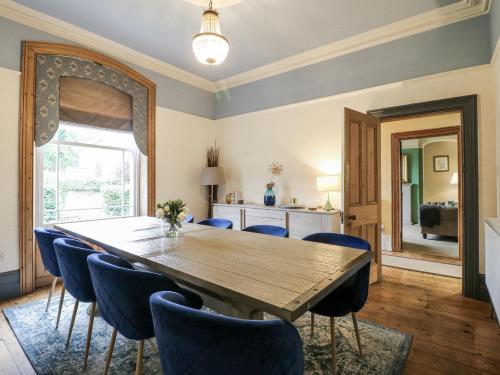 a dining room with a wooden table and blue chairs at Deeley House in Matlock