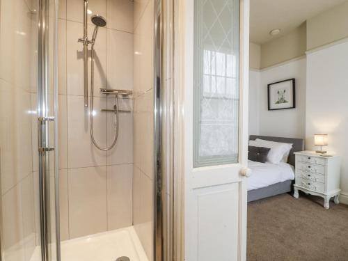 a bathroom with a walk in shower next to a bed at Deeley House in Matlock