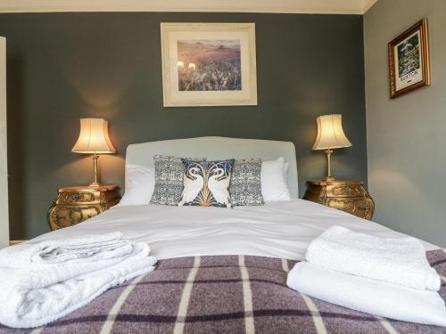 a bedroom with a large white bed with two lamps at Deeley House in Matlock