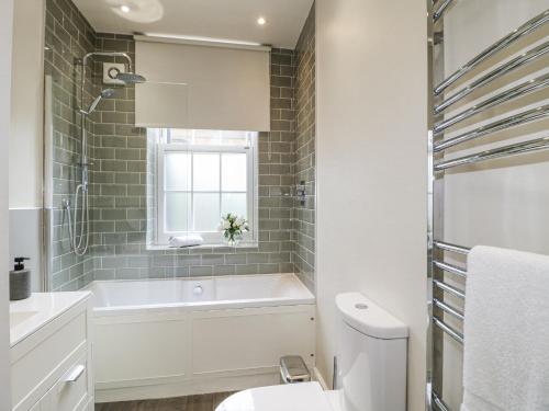 a bathroom with a tub and a toilet and a window at Deeley House in Matlock