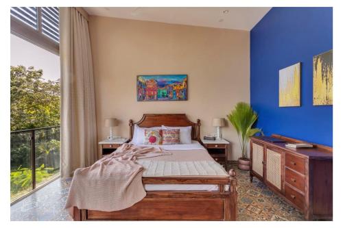 a bedroom with a bed with a blue wall at Dia Hotels and Homes Nerul Goa - Villas and Apartments in Nerul