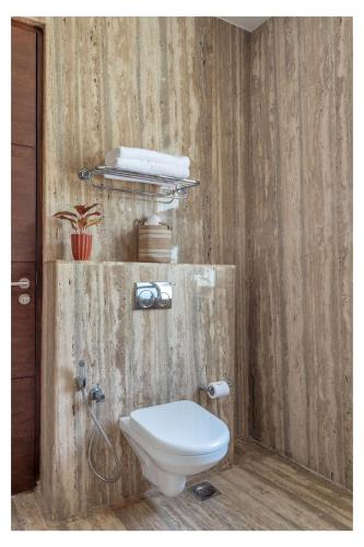 a bathroom with a toilet and a wooden wall at Dia Hotels and Homes Nerul Goa - Villas and Apartments in Nerul