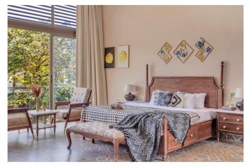 a bedroom with a bed and a chair and a window at Dia Hotels and Homes Nerul Goa - Villas and Apartments in Nerul