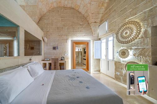 a bedroom with a large bed in a stone wall at Corte Dei Granai Meeting & SPA - Raro Rooms Collection in Maglie
