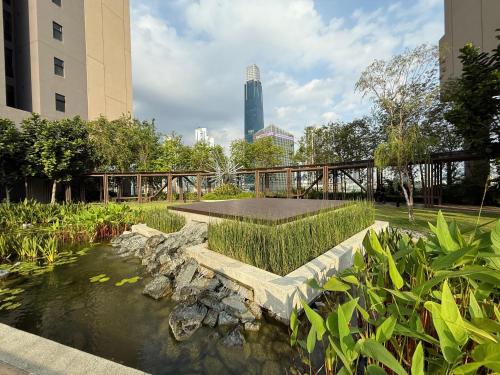 a pond in a park with a bridge and buildings at Axon Suite Bukit Bintang By Luna in Kuala Lumpur