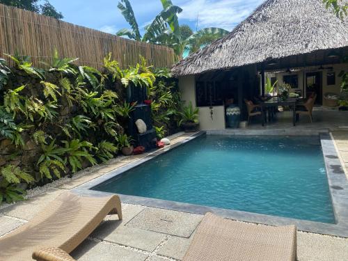 a swimming pool in front of a house with a table at Casa Manalo Guest House in Puerto Princesa City