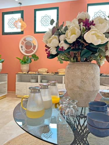 a glass table with a vase with flowers on it at Soho Boutique Tetuán in Tetouan