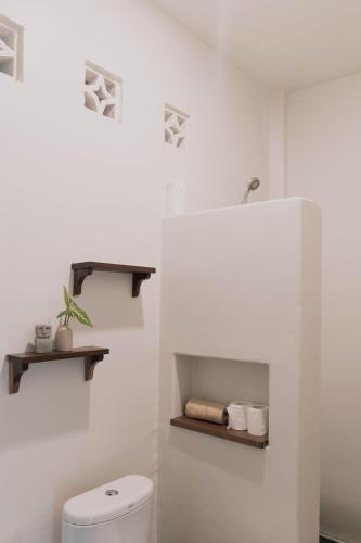 a white bathroom with a toilet and a sink at Nalua Boutique Hotel in Kuta Lombok