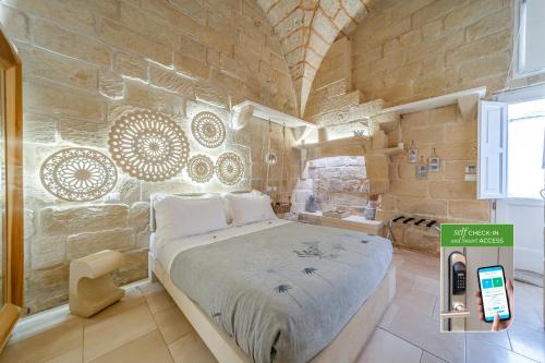 a bedroom with a large bed in a stone wall at Corte Dei Granai Meeting & SPA - Raro Rooms Collection in Maglie