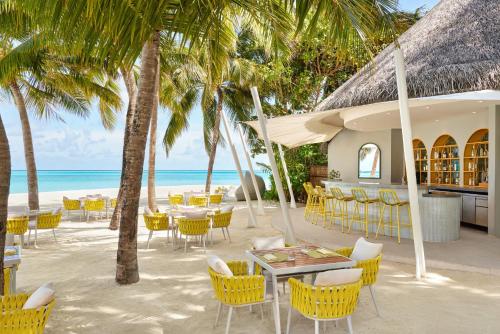 a restaurant on the beach with chairs and tables and palm trees at Niyama Private Islands Maldives in Dhaalu Atoll