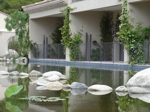 a pond in front of a house with rocks at Maison du Lac in Les Angles Gard