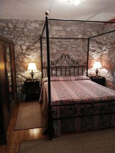a bedroom with a bed and a stone wall at Posada Valle De Guriezo in Ríoseco