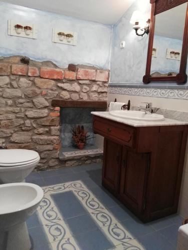 a bathroom with a sink and a stone fireplace at Posada Valle De Guriezo in Ríoseco