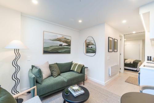 a living room with a green couch and a bedroom at 1BR Alpha APT - Central Stay Top Amenities in Wellington