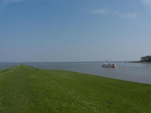 a boat in the water near a grassy hill at Ferienwohnung Abbey Road in Varel