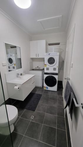 a small bathroom with a sink and a washer and dryer at Barrier Townhouse in Port Douglas