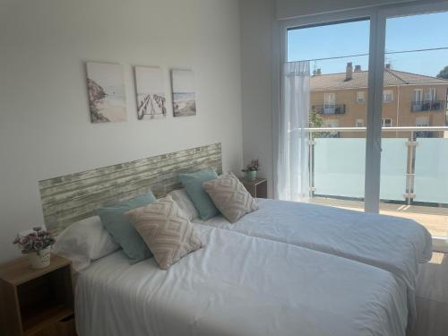 a bedroom with a white bed with a large window at Apartamentos AriNai climatizado y con garaje in Los Arcos