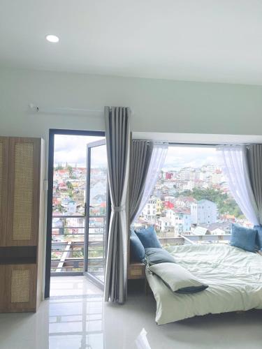a bedroom with a bed and a large window at LENA Home in Da Lat