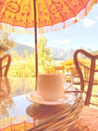 a cup of coffee sitting on a table under an umbrella at SEIN Boutique Suites - ADULTS ONLY in Gosau