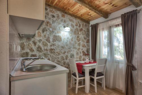 a kitchen with a sink and a table with chairs at Harmonia Bungalows & Pool in Sveti Stefan
