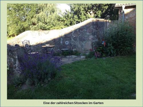 a garden with a stone wall and a table and flowers at Grüne Idylle in Borrentin