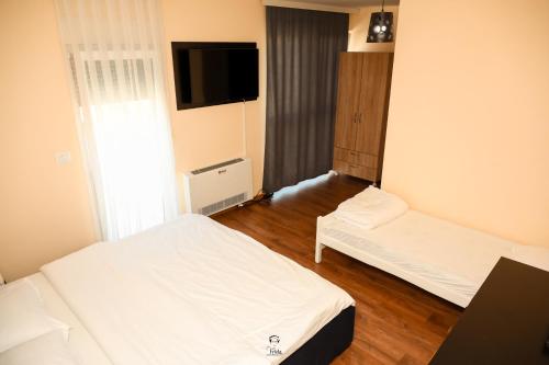 a hotel room with two beds and a flat screen tv at Hotel & Restaurant Frida in Gjakove