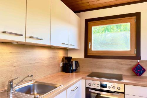 a kitchen with white cabinets and a sink and a window at Simi in Simonsberg