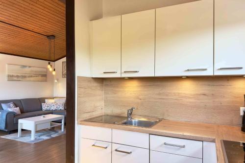 Una cocina con gabinetes blancos y una sala de estar. en Simi, en Simonsberg