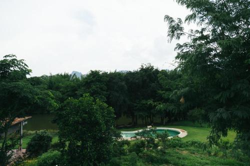a pool in the middle of a park with trees at Chong khaep aingkwai resort Saiyok in Sai Yok