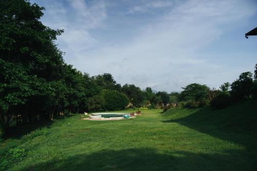 a grassy field with a swimming pool in the middle of it at Chong khaep aingkwai resort Saiyok in Sai Yok