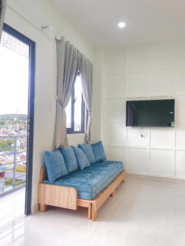 a couch with blue pillows in a room with a window at LENA Home in Da Lat