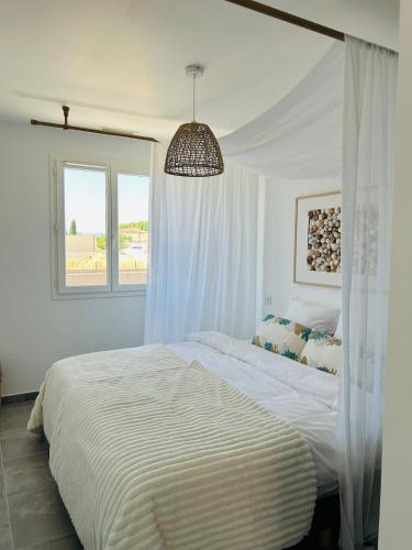 a white bedroom with a bed with a canopy at Le Cottage de Felix in Canet d'Aude