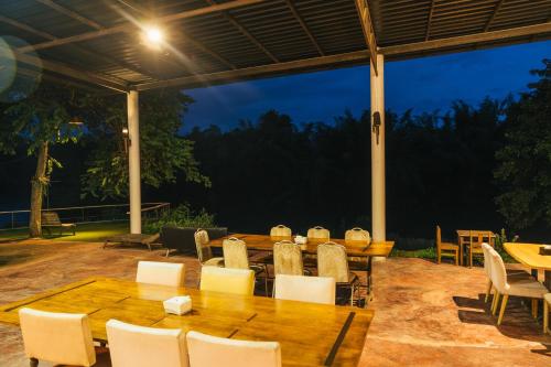 a patio with wooden tables and chairs and a night at Chong khaep aingkwai resort Saiyok in Sai Yok